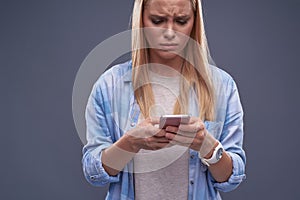 Upset young lady in blue shirt using cellphone