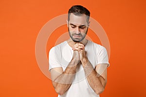 Upset young man in casual white t-shirt posing isolated on bright orange wall background studio portrait. People sincere