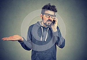 Upset young man talking on cellphone feeling annoyed and frustrated