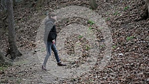 Upset young man walking in forest, throwing stone with annoyance, helpless anger