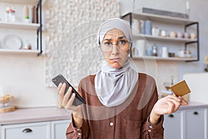 Upset young muslim woman wearing hijab feeling frustration and problems with credit card account and finances. He