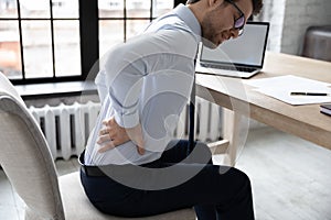 Upset young office employee suffering from chronic backache