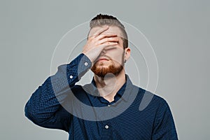 Upset young successful businessman posing over grey background. Copy space.