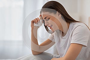 Upset young woman crying and wiping tears with tissue