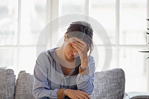 Upset young woman hiding face, crying, thinking about problem