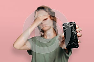 Upset young woman holding her broken smartphone. Phone screen need to repair