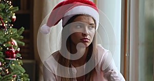 Upset young woman lost in pessimistic thoughts under Xmas tree