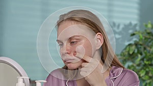 Upset young woman showing her finger on her problematic facial skin, pimples, black dots and comedones. Woman without