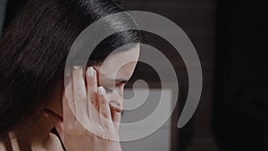 An upset young woman sitting near the bed, rubs against her temple, with closed eyes suffers from headache, painful sensations