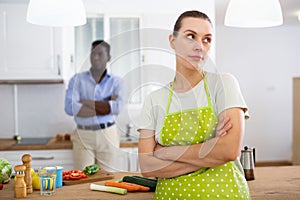 Upset young woman standing in kitchen after discord with husband