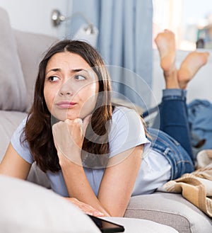 Upset young woman student lying at home on sofa