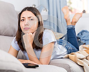 Upset young woman student lying at home on sofa