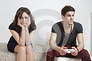 Upset young woman with young man playing video game