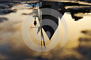 Upside down old windmill against bright sunset background