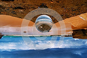 Upside-down shot of a crystal ball with the reflection of the sandy beach on a summer day