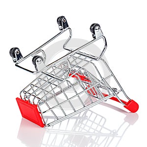 Upside down wheels empty chromed toy market shopping cart with red handle and plastic board on the front. White background with