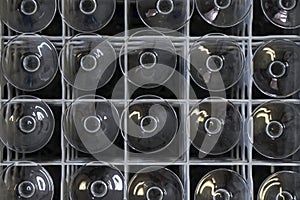 Upside-down wine glasses positioned in a plastic container with dividers forming a symmetrical pattern