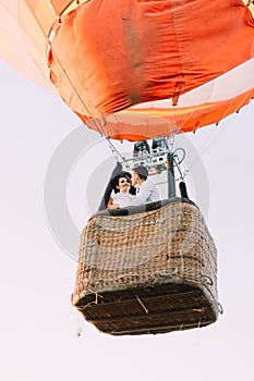 The upside view of the airballoon flying with the smiling vintage dressed newlyweds. photo