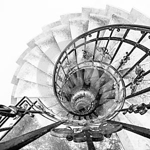 Upside view of indoor spiral winding staircase with black metal ornamental handrail