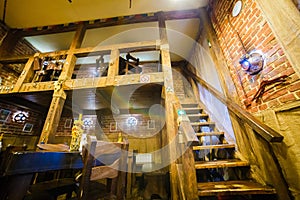 The upside view of the wooden staircases in the rustic cafe decorated with the kitchenware.