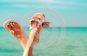 Upside woman feet and red pedicure wearing pink sandals, sunglasses at seaside. Funny and happy fashion young woman relax