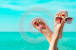 Upside woman feet and red pedicure wearing pink sandals, sunglasses at seaside. Funny and happy fashion young woman relax