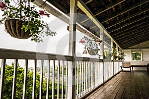 Upstairs patio/ balcony with hardwood flooring and hanging plants