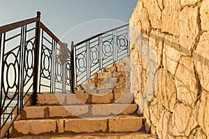 Upstairs steps with metal railings and limestone wall. Limestone texture on the stairs