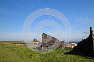 Upturned boats on Holy Island with view across the harbour