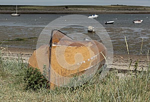 Upturned old orange coloured boat on the grass