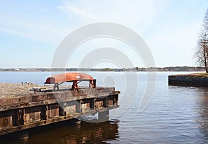 Upturned red boat on a jetty above the sea