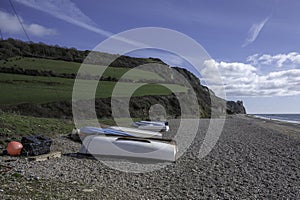 Upturned rowing boats on Branscombe Beach, Devon, on a sunny spring day.