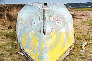 An upturned small boat washed up on the shoreline of a beautiful unspoiled beach