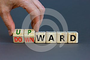 Upward or downward symbol. Businessman turns wooden cubes and changes the word `downward` to `upward`. Beautiful grey table, g