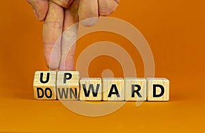 Upward or downward symbol. Businessman turns wooden cubes and changes the word `downward` to `upward`. Beautiful orange table,