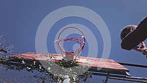 Upward view, a basketball ball hits the basket in the sports yard. The player successfully throws the ball into the hoop