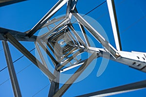 An upward view through a high voltage tower in a clear blue sky