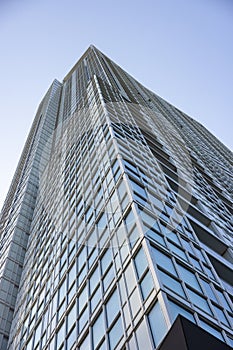 Upward view of modern skyscraper against blue sky