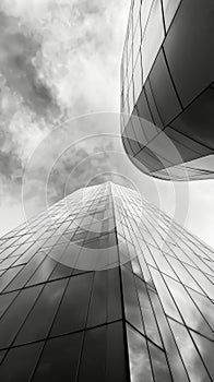 Upward view of a modern skyscraper against cloudy sky in black and white