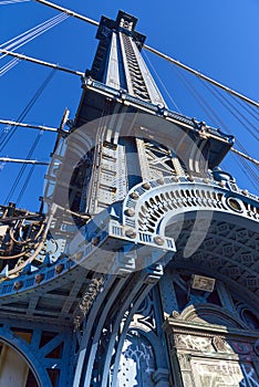 Upward view of a tower of the Manhattan Bridge with curved decorative steel work painted blue