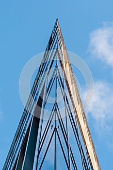 Facade of modern office building with glass and steel under blue sky, reflections and selective focus.