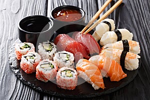Uramaki and nigiri sushi served in black plate closeup. horizontal photo