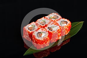 Uramaki philadelphia roll filled with salmon, cucumber, avocado and cream cheese. Philly rolls covered with red flying fish roe