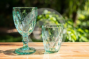 Uranium glass or Sapphire Crystal glass. Green tint color glassware vintage classic design old kitchenware on wooden table outdoor