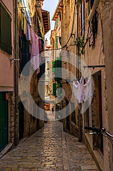 Urban alleyway with brick walls and sun-drenched laundry hung up to dry in Rovinj, Croatia