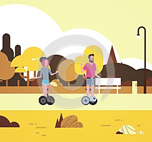 Urban autumn park outdoors activities man woman riding gyroscooter walking city buildings street lamps cityscape concept