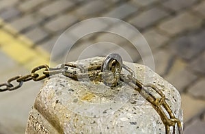 Urban background fence pillar cement iron weathered chain fixed on a blurred background of a stone square