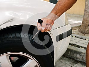 Urban banditry. Hand puncture car tire with punch