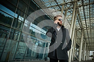 Urban business man in sunglasses talking smart phone traveling walking outside