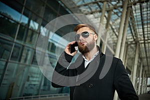 Urban business man in sunglasses talking smart phone traveling walking outside